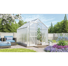 Kas in tuin met planten en zithoek.