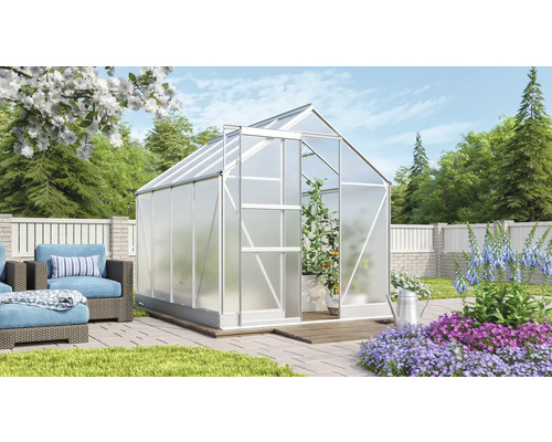 Kas in tuin met planten en zithoek.