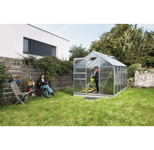 Tuinscene met kas, vrouw en kind aan het tuinieren