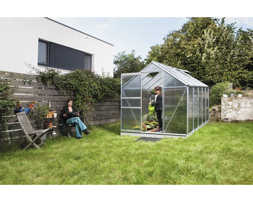 Tuinscene met kas, vrouw en kind aan het tuinieren