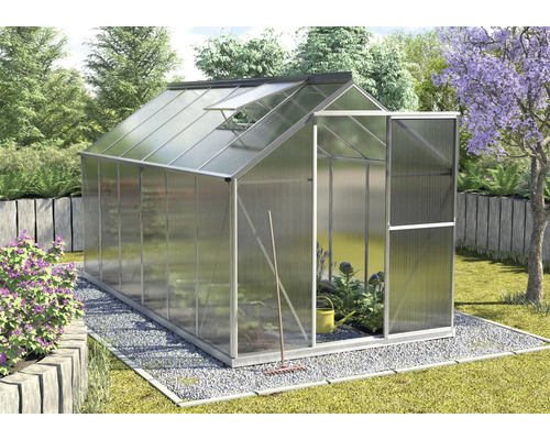 Tuinkas met open deur en dakraam in een tuin.