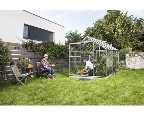 Tuinkas in een tuin met twee vrouwen, één aan het tuinieren, de ander zittend.