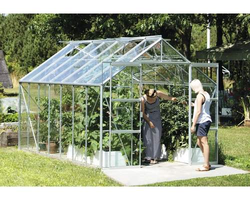 Kas met planten en twee personen in de tuin