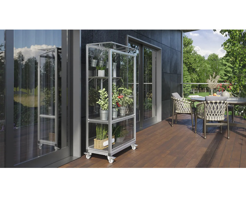 Een buitenscène met een plantenrek op wielen gevuld met diverse planten in potten, geplaatst op een terras naast een tafel met stoelen.