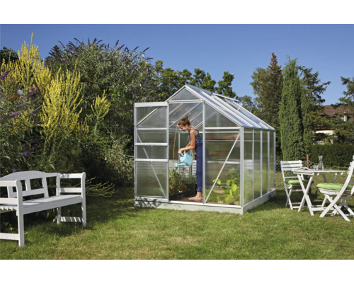 Kas in de tuin met een vrouw die planten water geeft