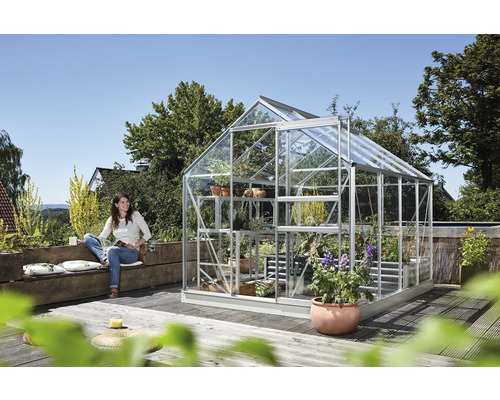 Serre met planten en een vrouw zittend op een bank
