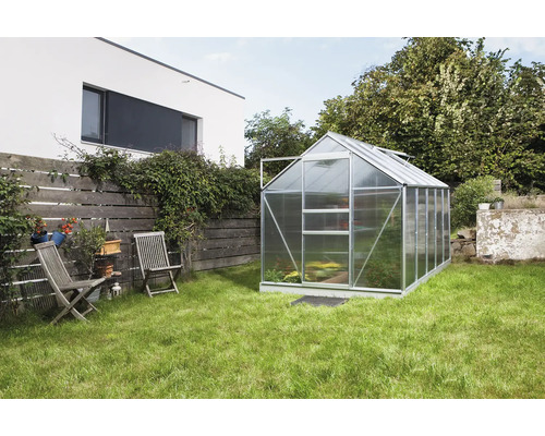 Kas in tuin met gazon en tuinmeubelen