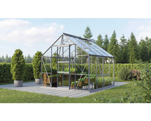Glazen kas met planten in een tuin.
