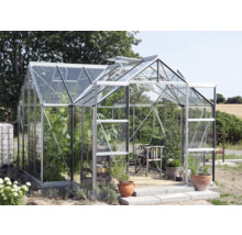 Kas met planten, stoel en potten in de tuin