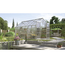 Kas met transparante wanden in een tuin met beplanting en terras