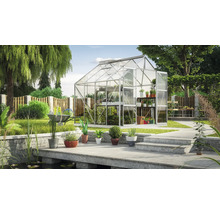 Tuinscene met kas, planten en tuinaccessoires