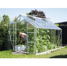 Kas in de tuin met vrouw die planten water geeft