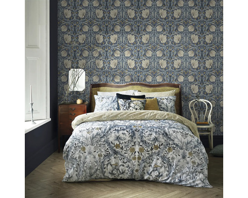 Slaapkamer met bloemenbehang, bed met bloemmotief beddengoed, nachtkastje en stoel.