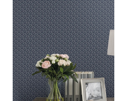 Behang met bloemenmotief, vaas met bloemen, boeken en fotolijst op een tafel.