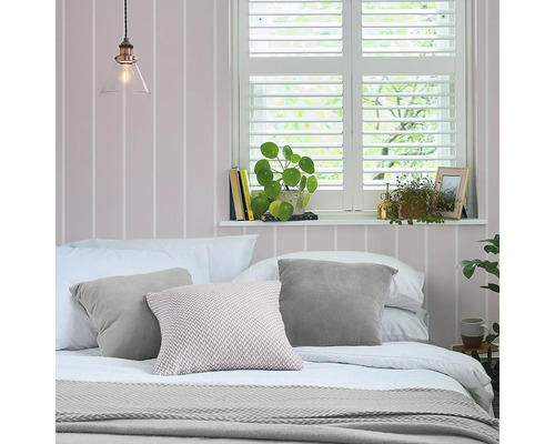 Slaapkamer met bed, kussens, plaid, jaloezieën en kamerplanten