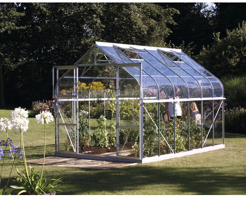 Kas met planten en tuin op de achtergrond