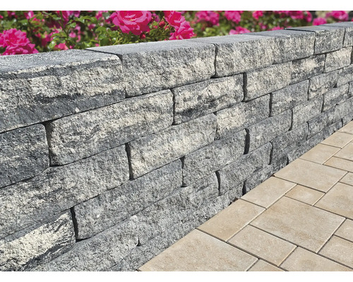 Close-up van een grijze tuinmuur gemaakt van stenen naast straatstenen