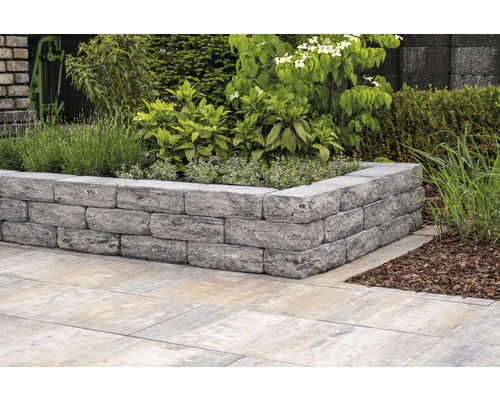 Tuinmuur van stenen met beplanting en tegels