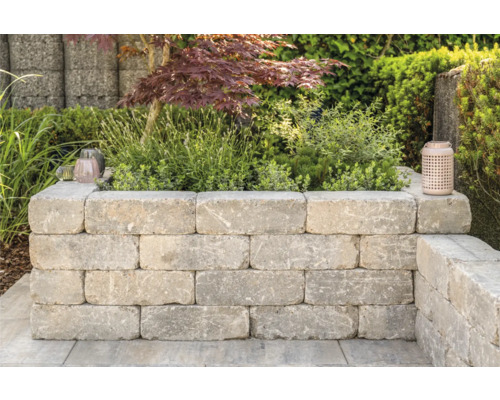 Verhoogde tuinbed van betonstenen in tuin met planten