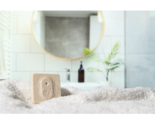 Vierkante, beige douchewisser op een handdoek in een badkamer.