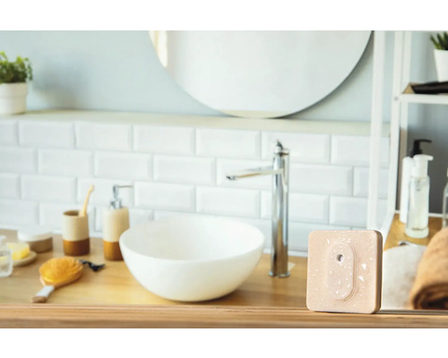 Moderne badkamer met wastafel, kraan en een vierkant, beige product op een houten tafel