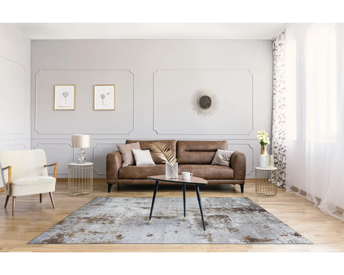 Woonkamer met bruine bank, vloerkleed, fauteuil en tafel