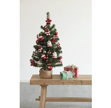 Versierde kunstkerstboom met geschenken op een houten tafel.