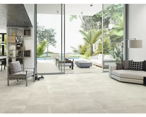 Lichte woonkamer met tegelvloer, bank en uitzicht op de tuin