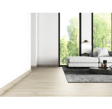 Lichte woonkamer met bank, tapijt, tafel en groot raam met uitzicht op groen.