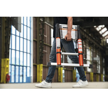 Een persoon draagt een telescoopladder in een interieur.