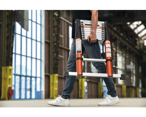 Een persoon draagt een telescoopladder in een interieur.