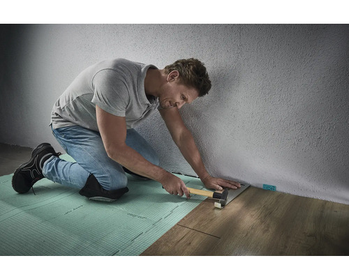 Man legt laminaat met een hamer en slagblok op isolatiemateriaal
