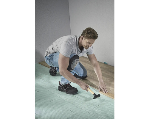 Man legt laminaatvloer met hamer en ondervloermat.