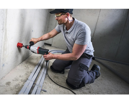 Vakman boort een gat in een muur met een boormachine.
