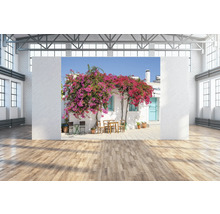 Scene met een witte gevel van een huis, bedekt met een bloeiende bougainville, en een kleine buitenzitgroep.