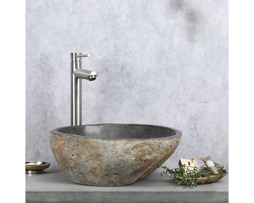 Steen wastafel met kraan en badkameraccessoires op een werkblad