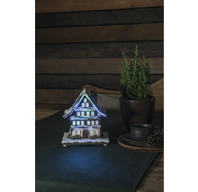 Decoratief verlicht huis naast potplant en kopje