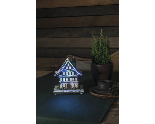 Decoratief verlicht huis naast potplant en kopje