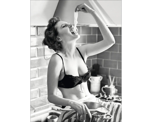 Een vrouw eet spaghetti in een keuken. Een vrouw eet spaghetti in een keuken.