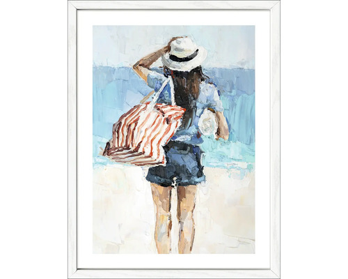Schilderij van een vrouw op het strand met hoed en tas in een witte lijst