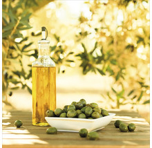 Olijfolie fles en groene olijven in schaal op houten tafel