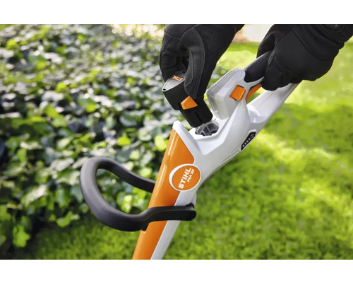 Een persoon plaatst een batterij in een draadloze grastrimmer.