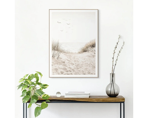 Decoratieve ingelijste muurafbeelding met strandthema boven een consoletafel