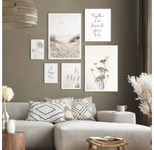 Woonkamer met bank en diverse muurafbeeldingen met plantmotieven en strandgezichten