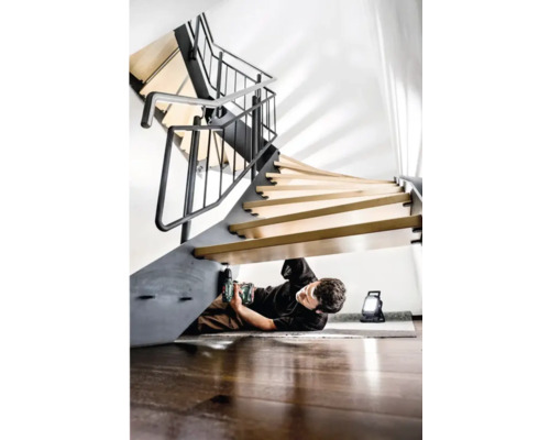 Man monteert wenteltrap met accuboormachine en bouwlamp