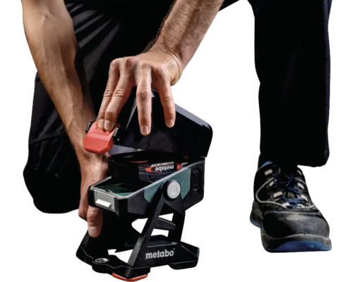 Iemand opent een Metabo bouwlamp op accu om de accu te vervangen.