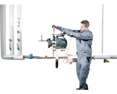 Een installateur monteert een tuinpomp aan een leidingsysteem.