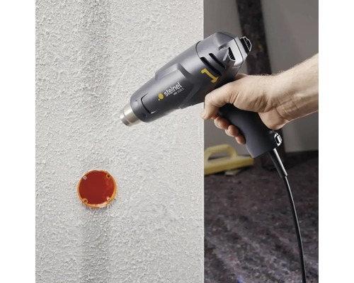 Heteluchtpistool in gebruik op een muur