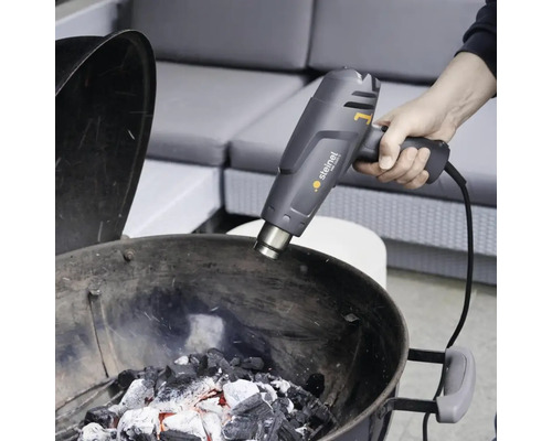 Persoon steekt houtskool aan met een Steinel heteluchtpistool.