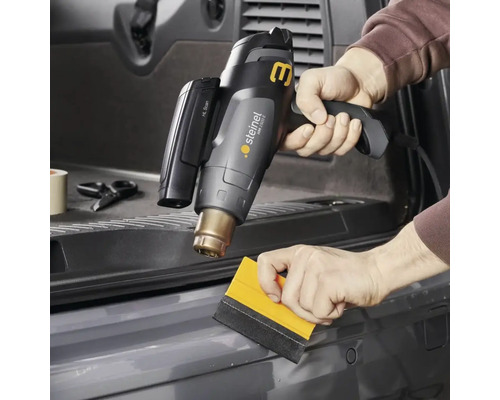 Heteluchtpistool in gebruik voor het aanbrengen van folie met een rakel.